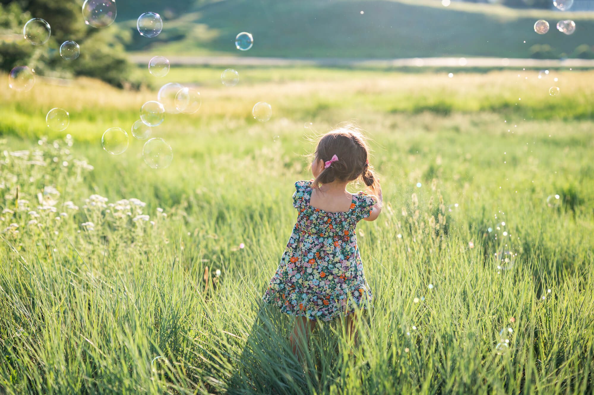 child playing in a grass field with bubbles